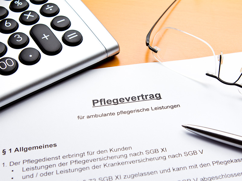 Tisch mit Pflegevertrag Dokumenten Taschenrechner Brille und Stift zur Planung von Pflegedienst in Flensburg Kosten und Leistungen