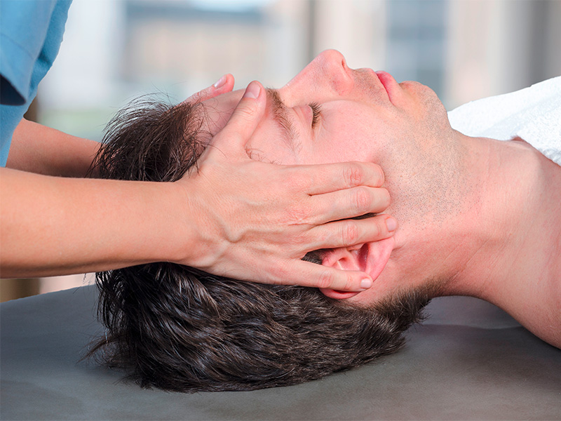 Physiotherapeut untersucht Kiefermuskulatur einer Patientin zur Behandlung craniomandibul&auml;rer Dysfunktion und muskul&auml;rer Verspannungen im Gesichtsbereich.