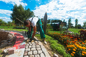 Handwerker verlegt Pflastersteine in einer Gartenanlage