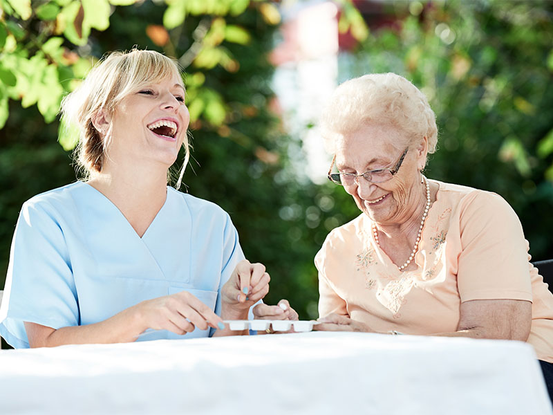 Pflegerin und Seniorin im Garten