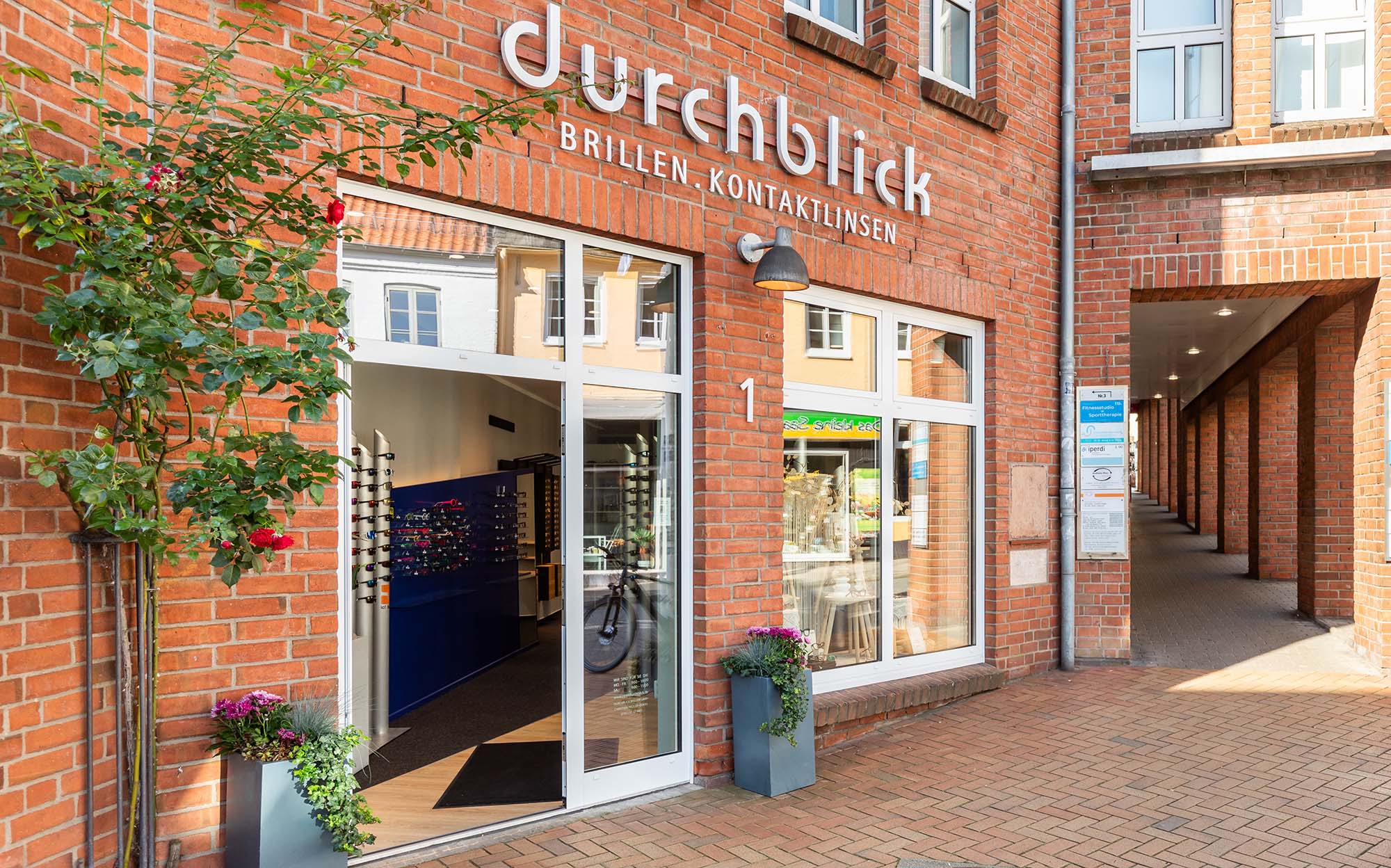 Außenansicht der Durchblick Brillen GmbH in Flensburg mit modernem Eingangsbereich und einladender Glasfassade im Stadtzentrum.