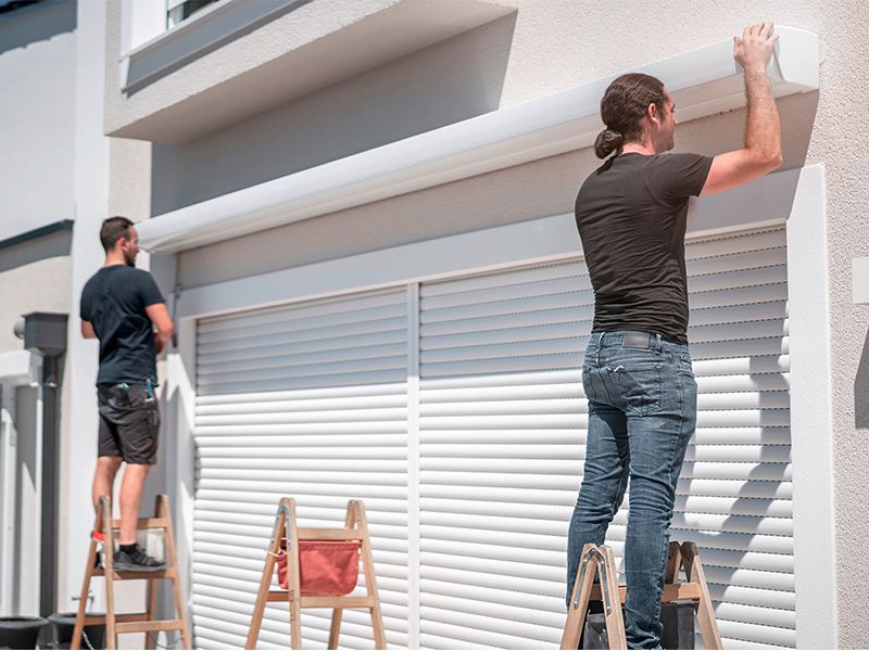 Zwei Handwerker montieren eine moderne Markise an einer Hauswand für professionellen Sonnenschutz in Flensburg