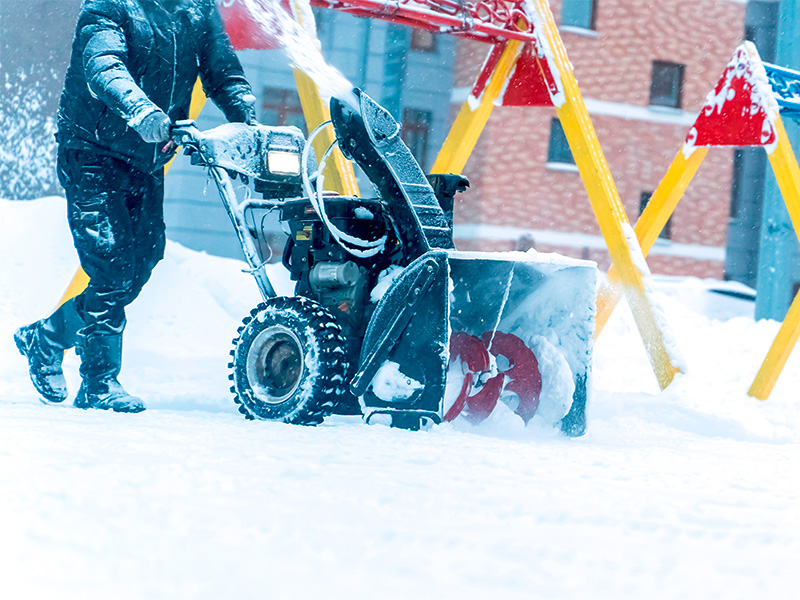 Winterdienstmitarbeiter entfernt Schnee mit Schneefräse im Hof eines Wohnhauses und erfüllt Räumpflicht in Satrup für sichere Wege im Winter